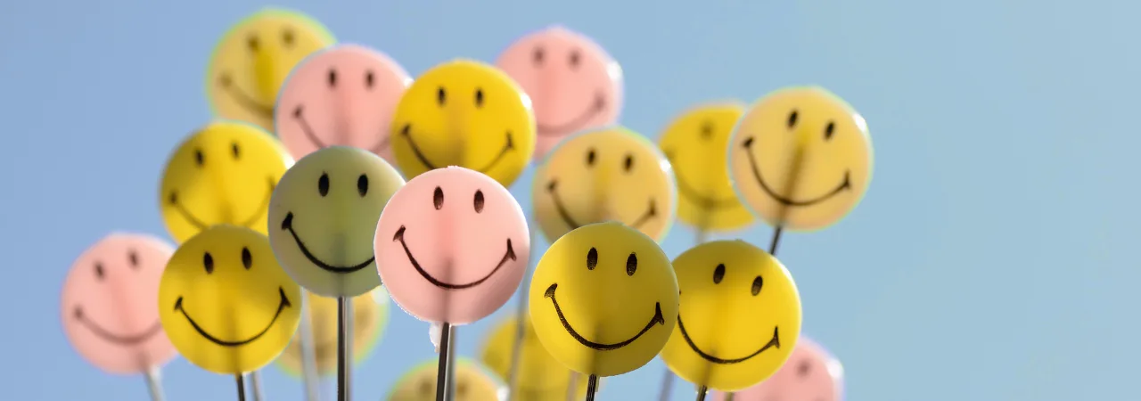 A blue background with smiley face baloons.