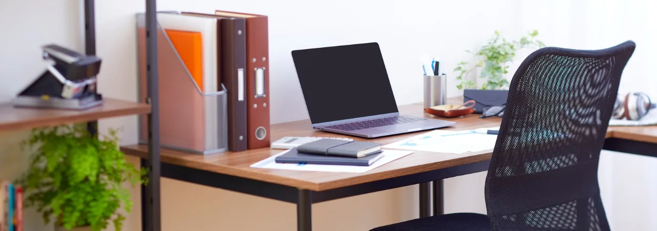 An image of a nicely decorated desk with a laptop on top p along with books and a black office chair