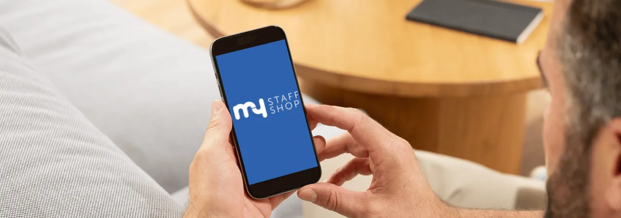 Person using the My Staff Shop employee discount app on a smartphone at home.