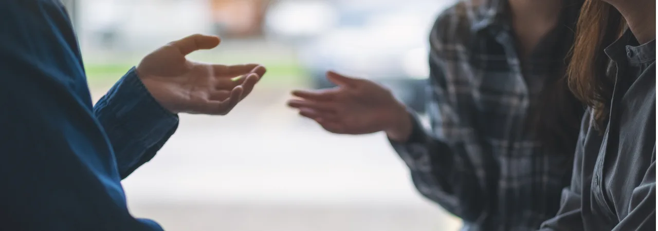 Co workers communicating, two people with their arms out talking
